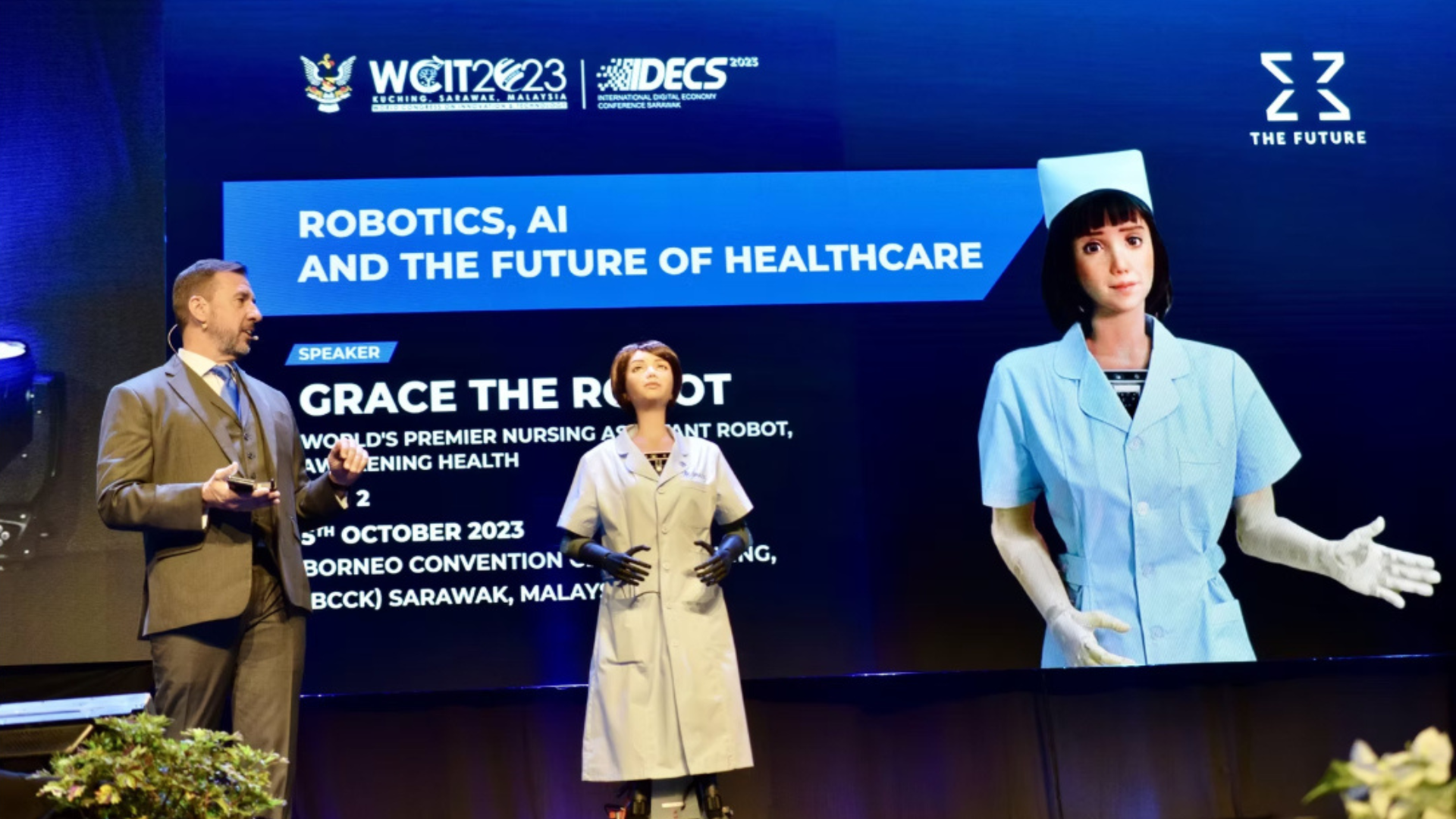 Bill Inman on stage with Sophia the Robot's sister, Grace
